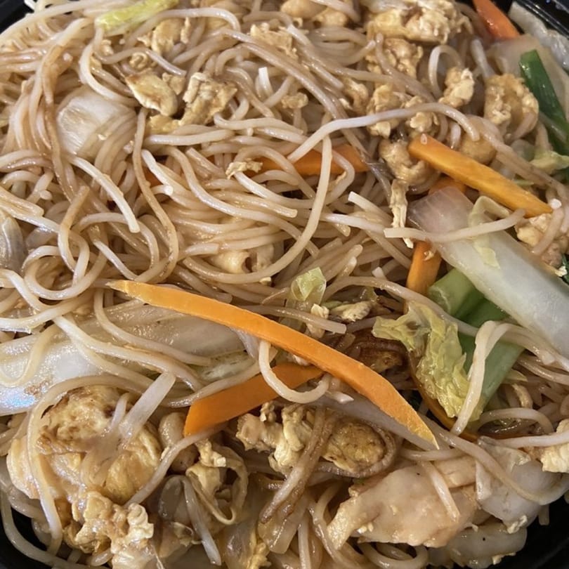 Close-up of Asian-fusion noodles with chicken, carrots, cabbage, and onions.