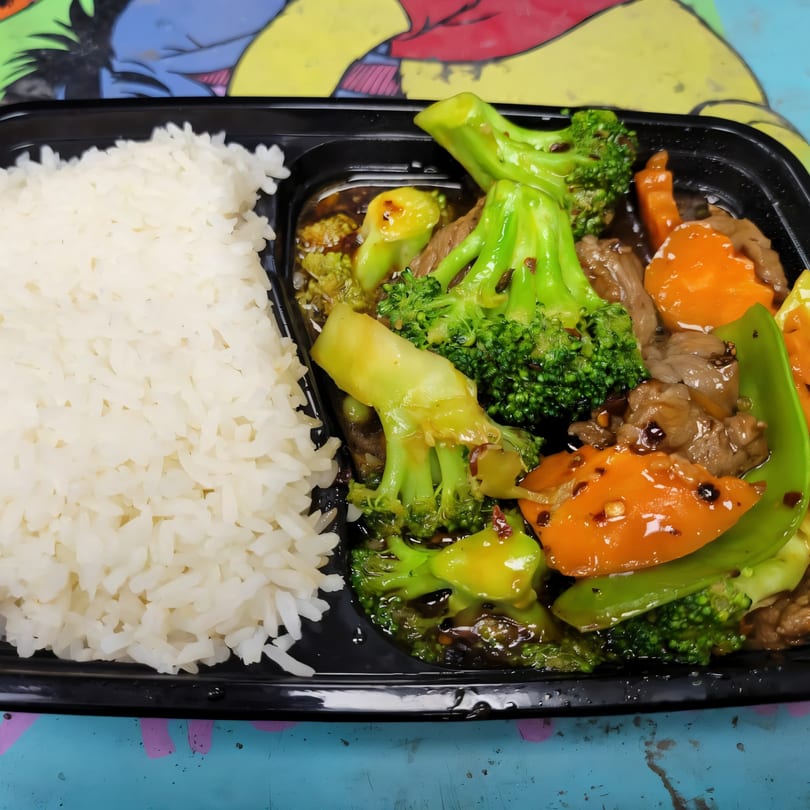 Asian-fusion beef and broccoli with carrots and peppers, served with white rice in a black container.