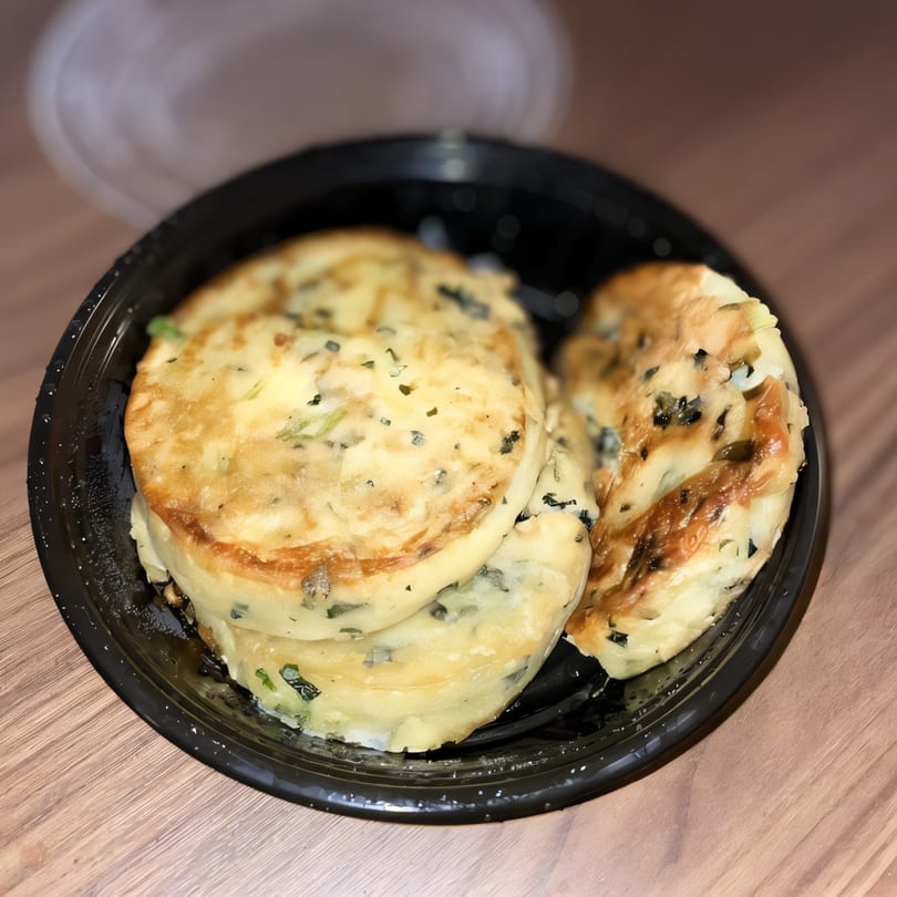Golden-brown scallion pancakes, a Bite of Asia specialty, served in a black takeout container.